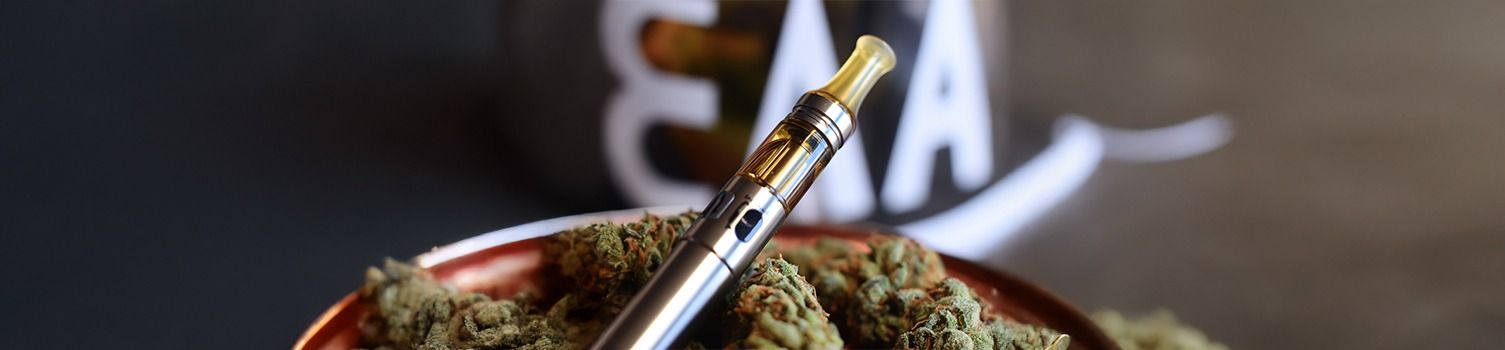bannière article blog "conserver son e-liquide au CBD" avec matériel de vape avec feuille de chanvre sur fond rose 